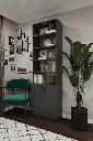 Koyu gri kitaplık, yeşil koltuk ve bitkiyle kurgulanmış köşede; açık raflar ve kapaklı bölüm bir arada görünüyor.